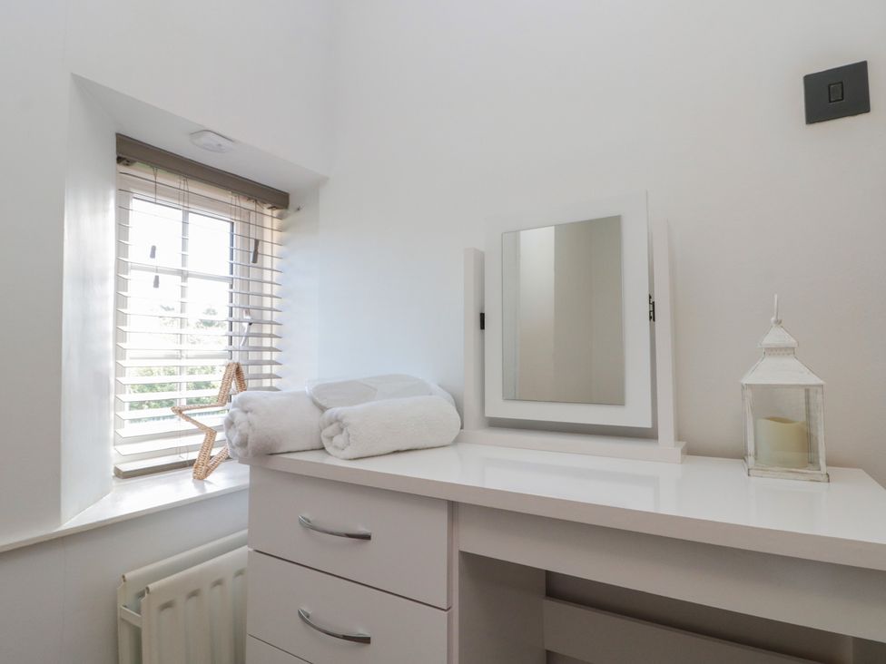 A bathroom with a mirror and towels on a vanity at Isla cottage