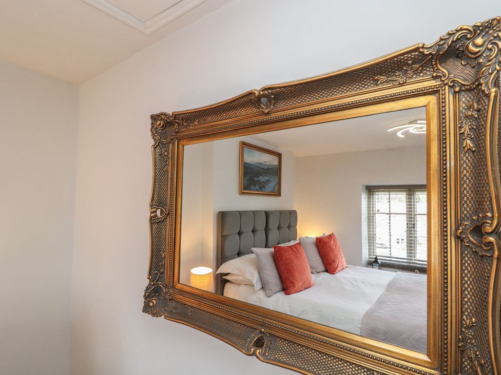 A bedroom with a bed and a mirror reflecting a painting at Isla cottage