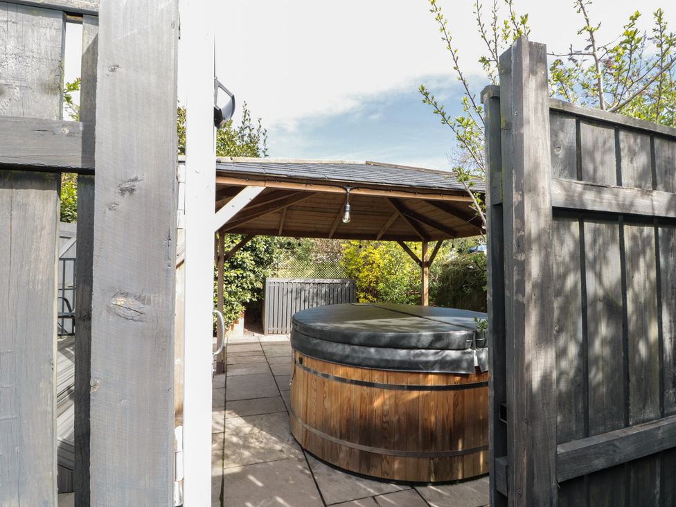 A hot tub under a gazebo in a garden at Isla cottage
