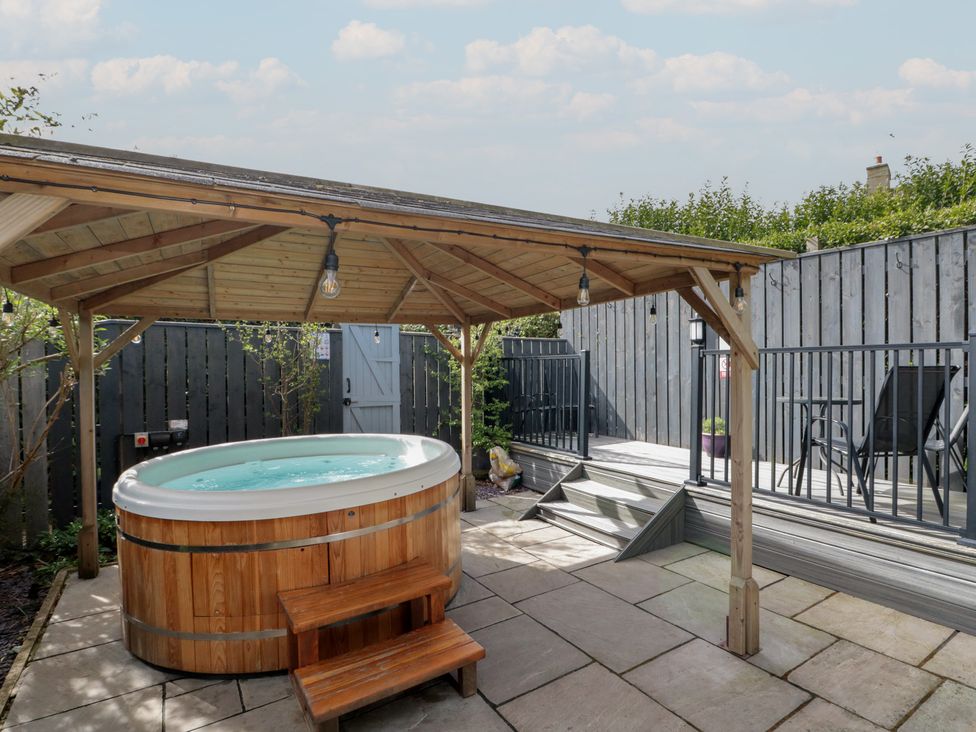 A garden with a hot tub and wooden steps at Isla cottage