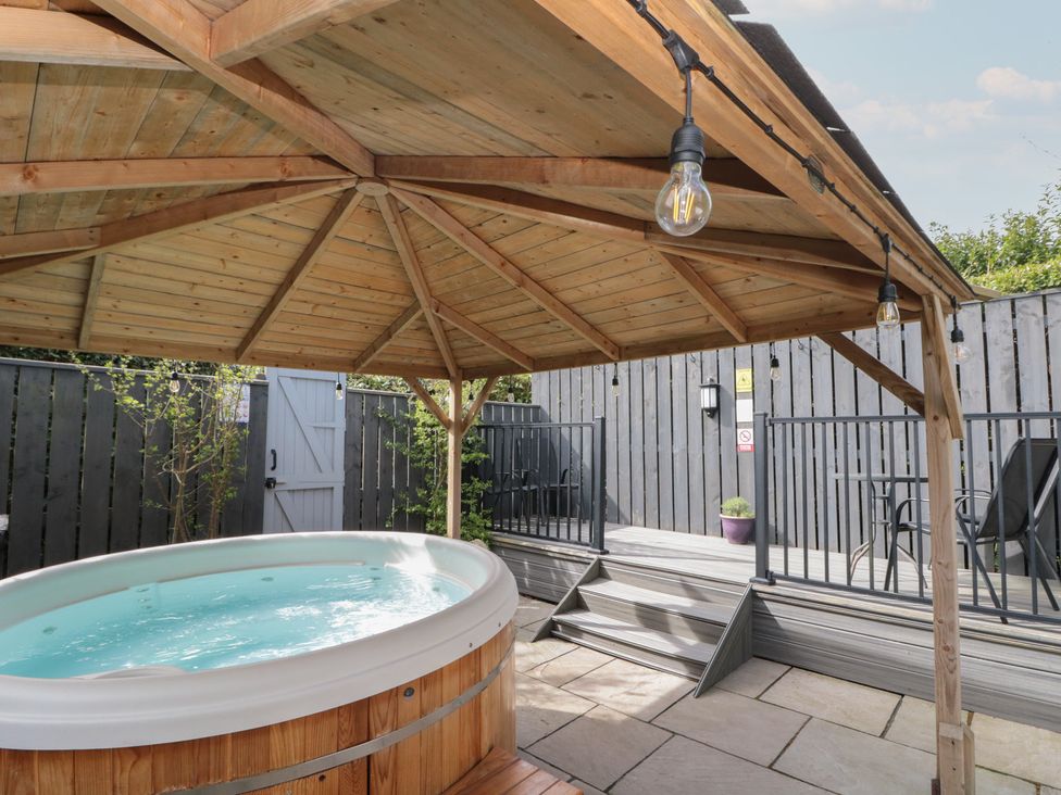 A hot tub under a wooden gazebo in a garden at Isla cottage