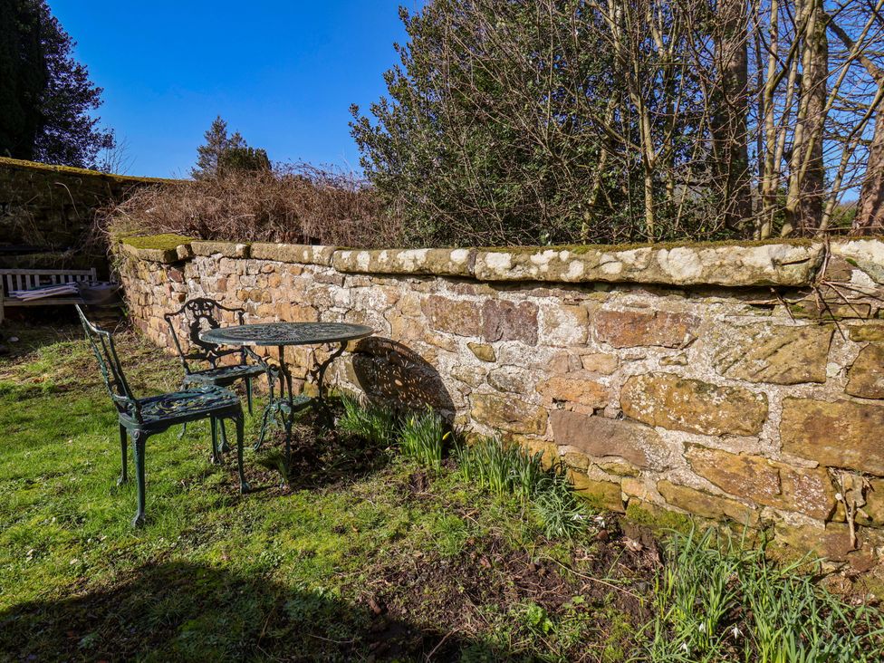 A garden area with a stone wall and outdoor furniture at 1 Rosedale Abbey