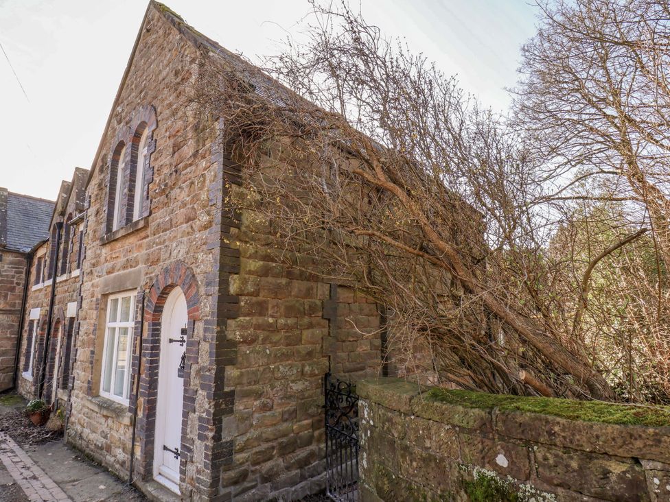 A stone building with tree branches leaning against it and a gate at 1 Rosedale Abbey
