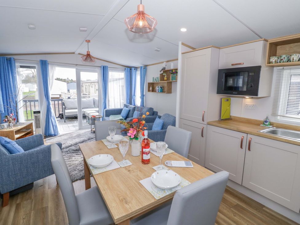 A dining room and living area with a table, chairs, and a couch at AV18 in Tiddington