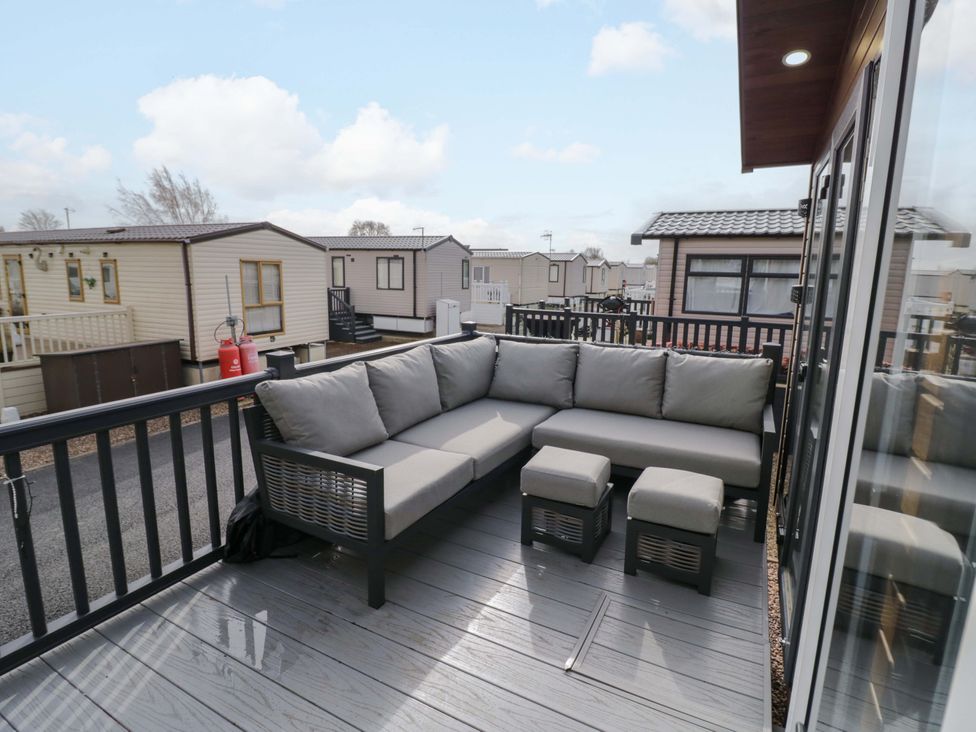 A seating area with a sofa and footstools on a deck at AV18 Tiddington