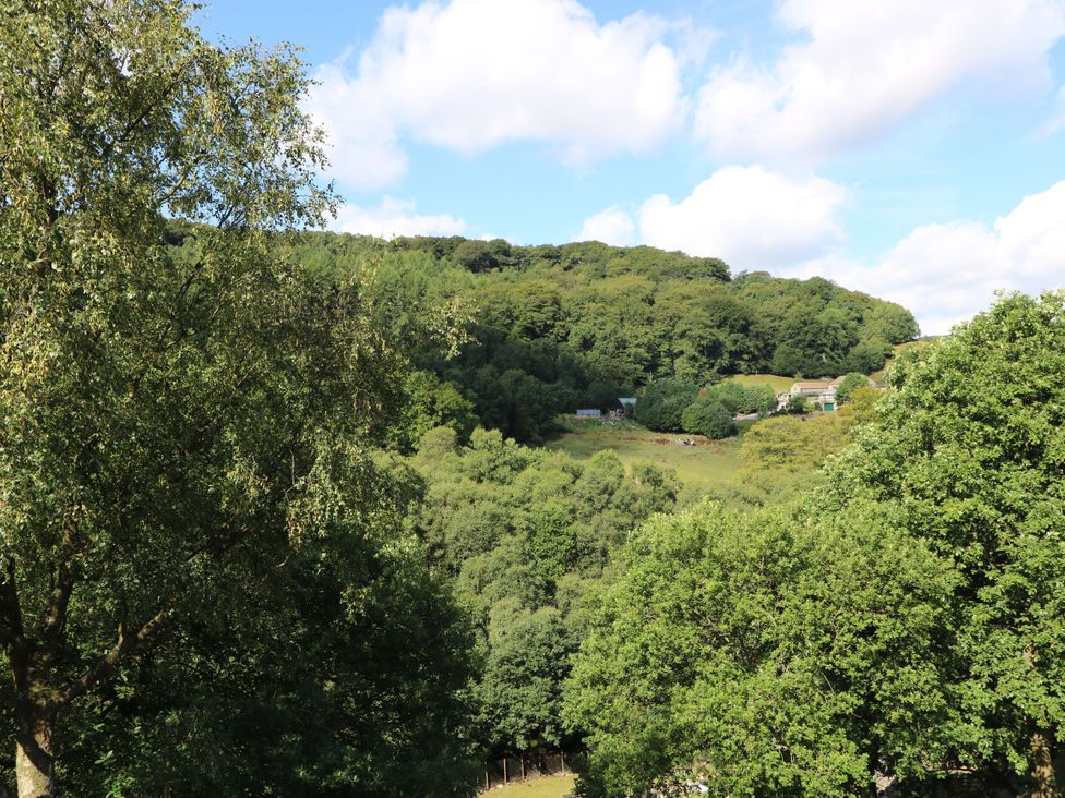 A view of hills and trees with houses in the distance at Victoria Wood View in Cragg Vale