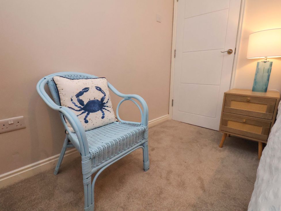 A living room with a blue chair and crab design pillow at Flat 1, 40 Hinderwell Lane