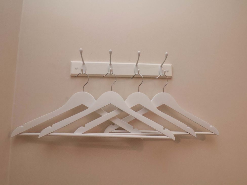 A set of white hangers on a wall hook in a closet