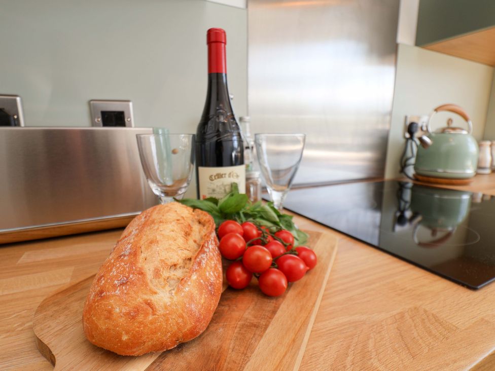 A kitchen with bread, wine bottle, glasses, and tomatoes at Seashells at Runswick Lodge, Runswick Bay