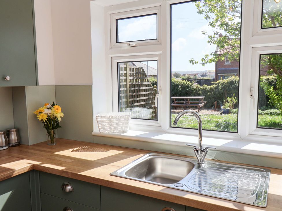 A kitchen with a sink and a window overlooking the garden at Seashells at Runswick Lodge Runswick Bay