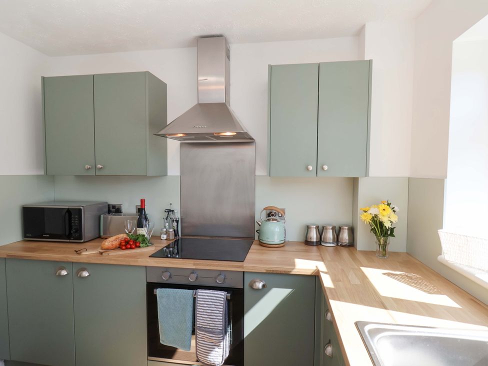 A kitchen with cabinets, stove, and microwave at Seashells at Runswick Lodge Runswick Bay