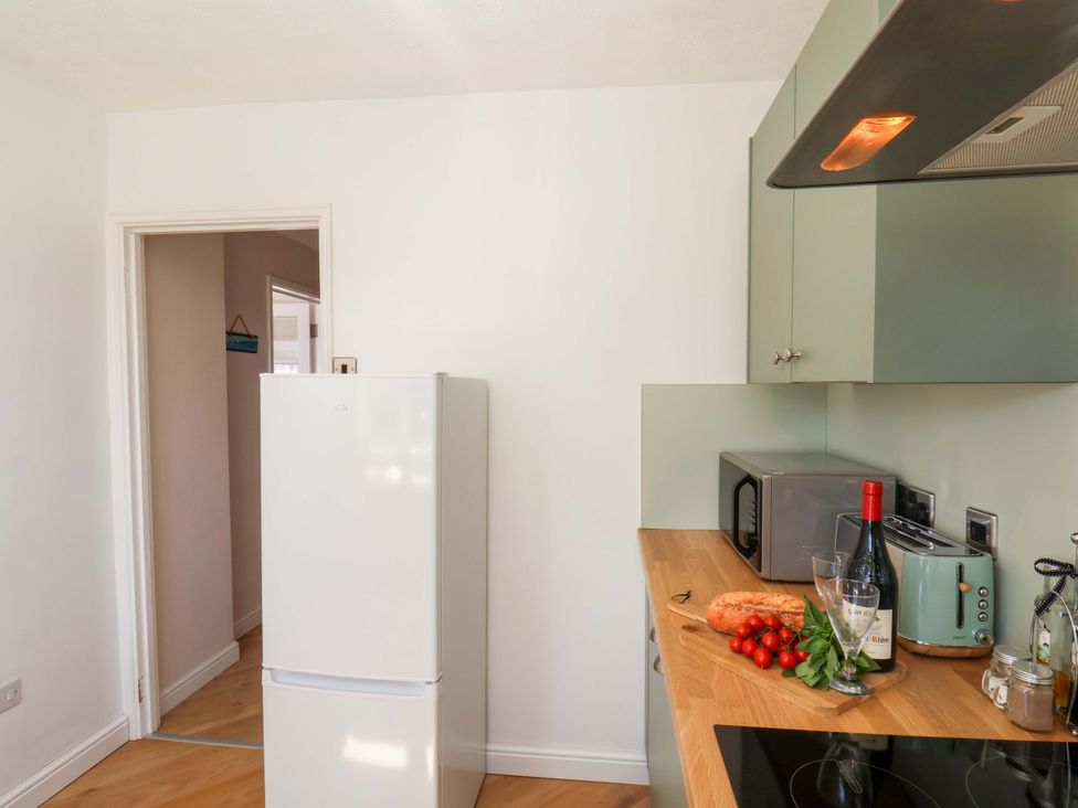 A kitchen with a fridge, bread, tomatoes, and wine bottle at Seashells at Runswick Lodge Runswick Bay