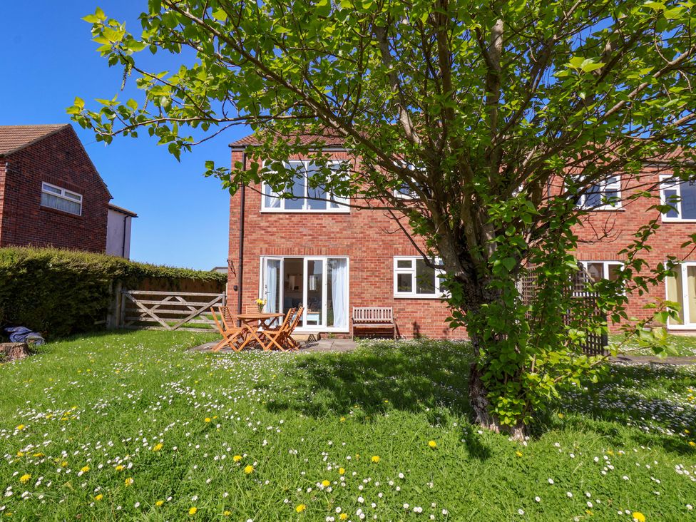 A garden with a tree and seating area at Seashells at Runswick Lodge Runswick Bay