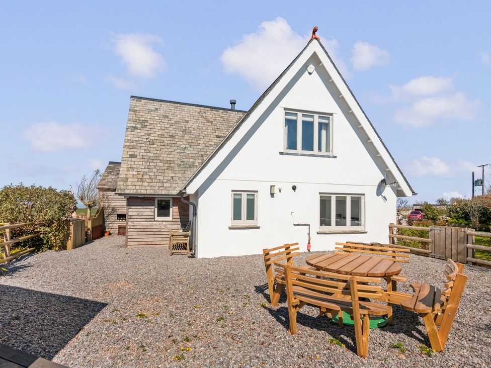 A house with a table and chairs on a gravel area at Capton Snug in Dartmouth