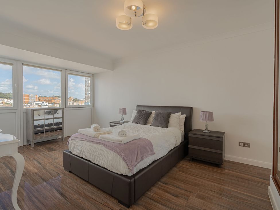 A bedroom with a bed and windows at Beachfront Penthouse Brighton