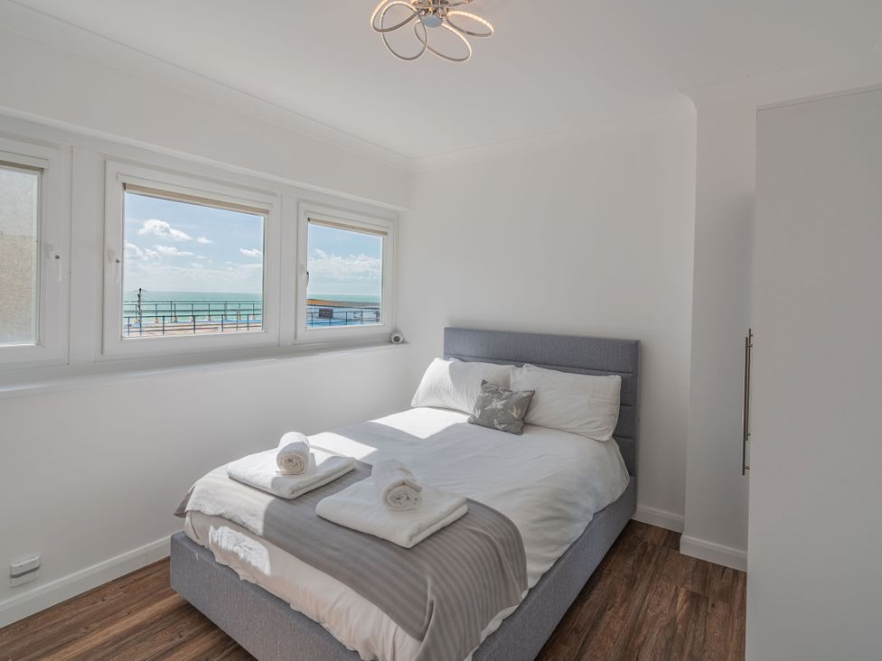 A bedroom with a bed and windows at Beachfront Penthouse Brighton