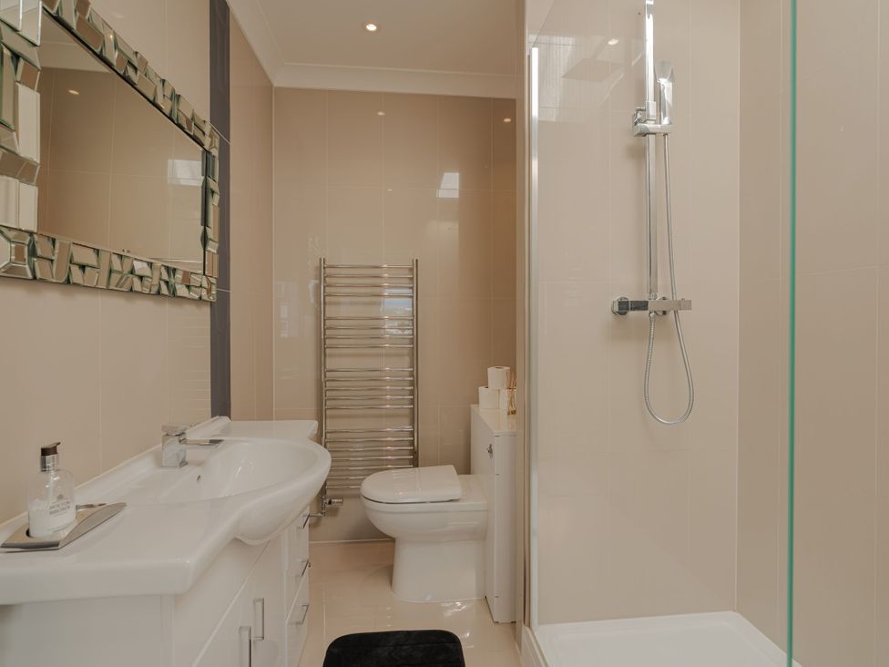 A bathroom with a mirror, sink, toilet, and shower at Beachfront Penthouse in Brighton