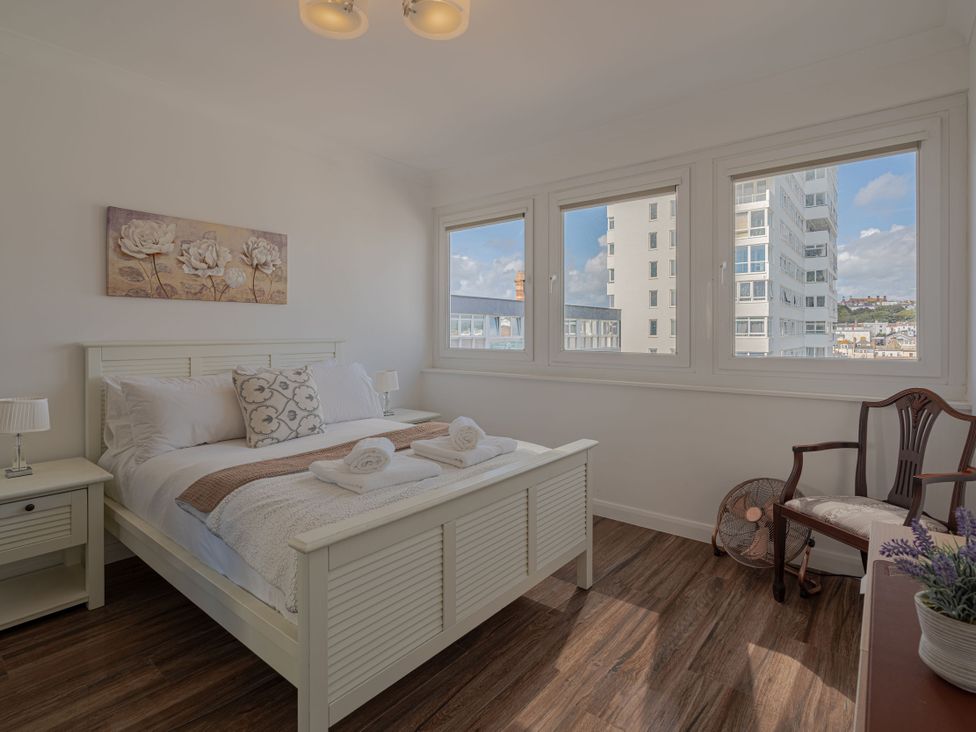 A bedroom with a bed and windows at Beachfront Penthouse in Brighton