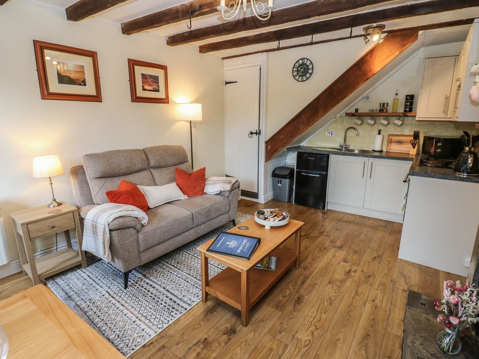 A living room with a sofa and kitchen area at Olive Cottage in Richmond