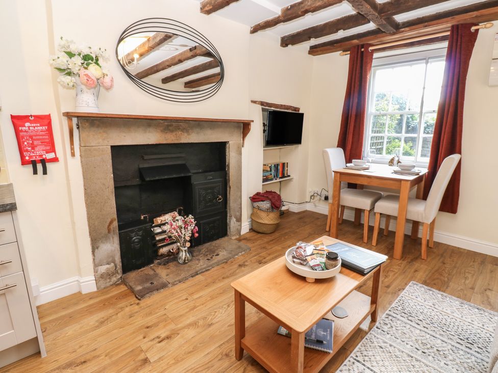 A living room with a fireplace and dining table at Olive Cottage in Richmond