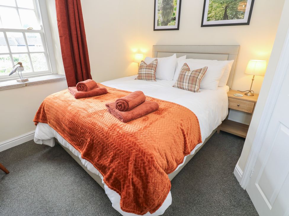 A bedroom with a double bed and towels arranged on it at Olive Cottage Richmond