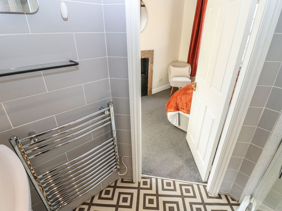 A bathroom with a towel rail and door leading to bedroom at Olive Cottage in Richmond