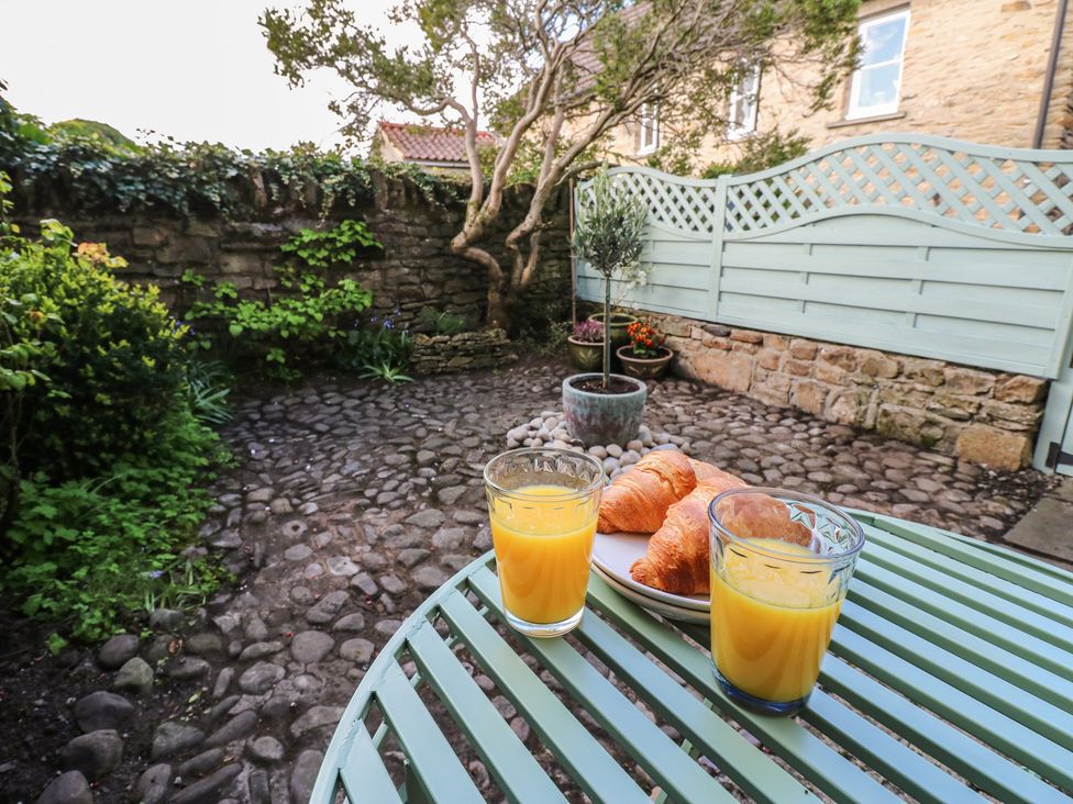 A garden with a table and two glasses of orange juice at Olive Cottage in Richmond