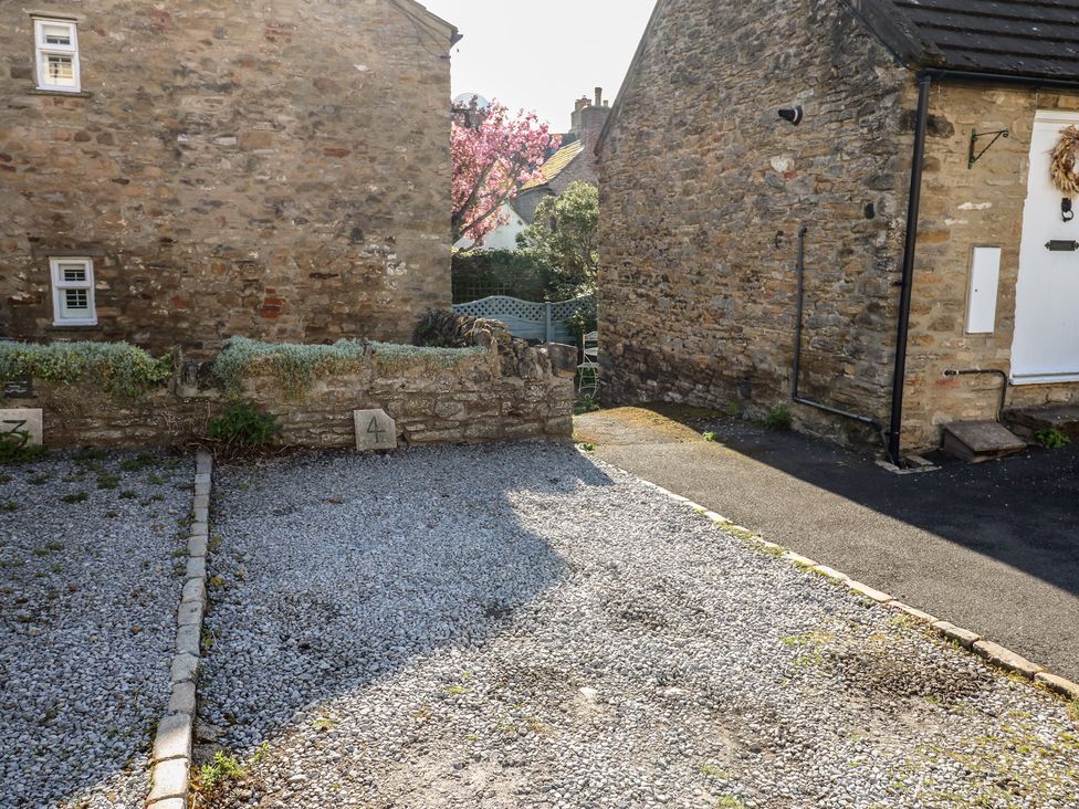 A gravel area with stone wall and numbered sections at Olive Cottage in Richmond