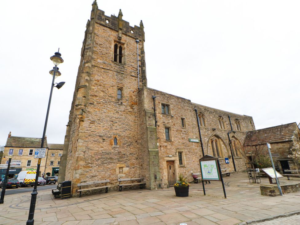 A stone tower and buildings with benches on a pathway in Richmond