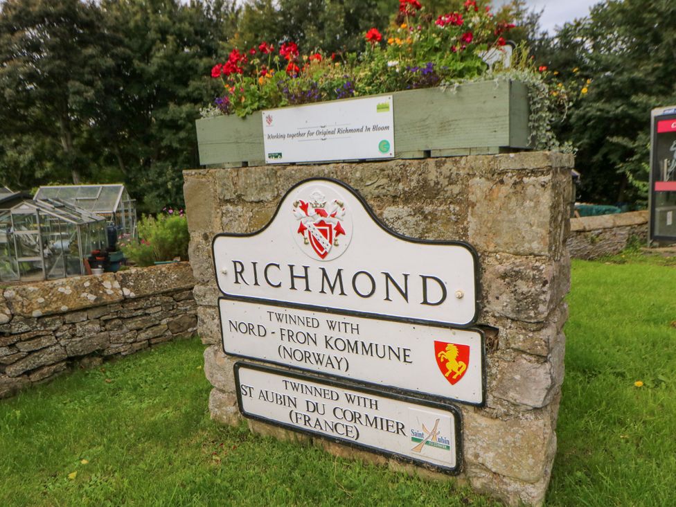 A sign for Richmond with flowers and greenhouses nearby at Olive Cottage Richmond