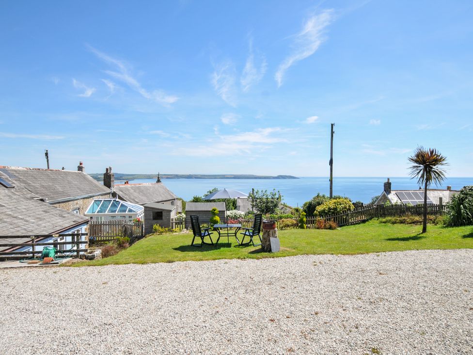 A garden area with a table and chairs overlooking the sea at Casa Mia in Porthpean near St Austell