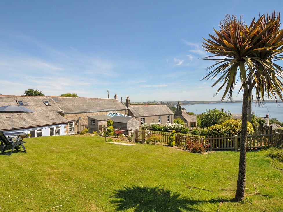 A garden area with a palm tree and ocean view at Casa Mia in Porthpean near St Austell