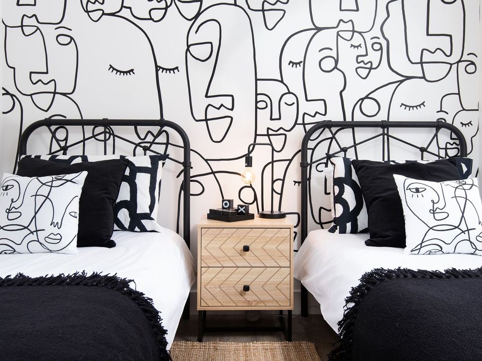 A bedroom with two beds and a patterned wall at Summerset Lodge