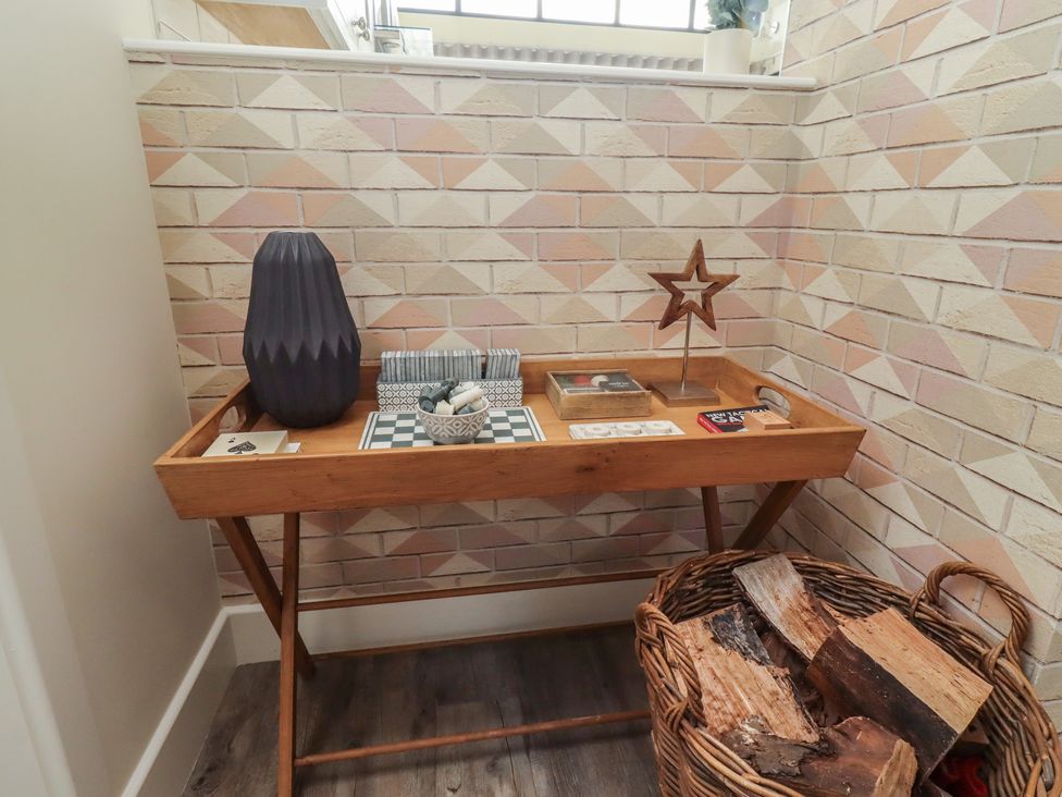 An entryway with a table, vase, and firewood at Summerset Lodge in Bamburgh