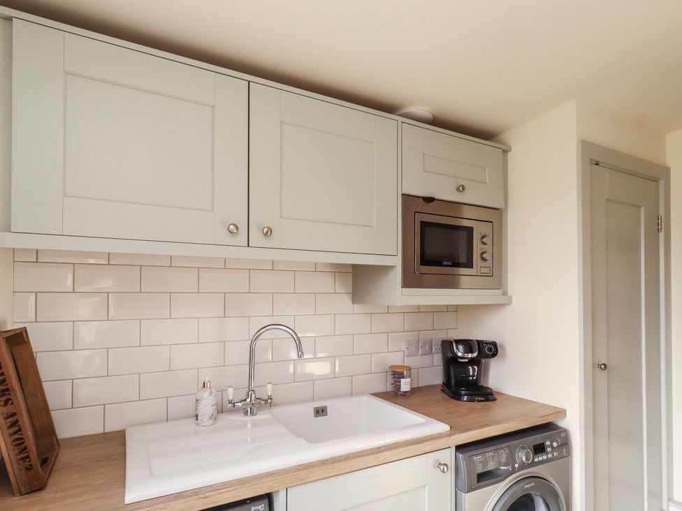 A kitchen with cabinets, sink, microwave, coffee machine, and washing machine at Summerset Lodge, Bamburgh