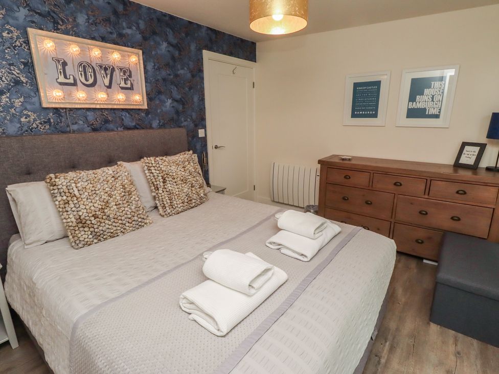 A bedroom with a bed and dresser at Summerset Lodge Bamburgh