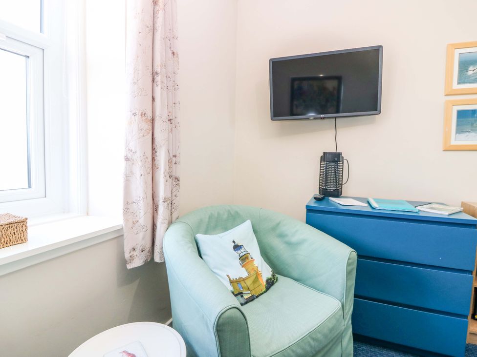 A small living room with an armchair and television at The Flaghouse at The Lighthouse St Abbs