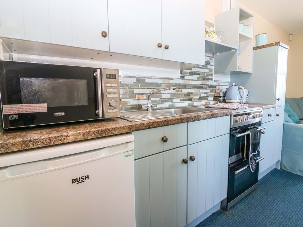 A kitchen with a microwave, sink, kettle, oven, and dishwasher at The Flaghouse at The Lighthouse St Abbs