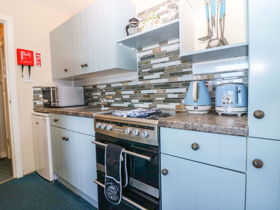 A kitchen with cabinets, oven, microwave, kettle and toaster at The Flaghouse at The Lighthouse St Abbs