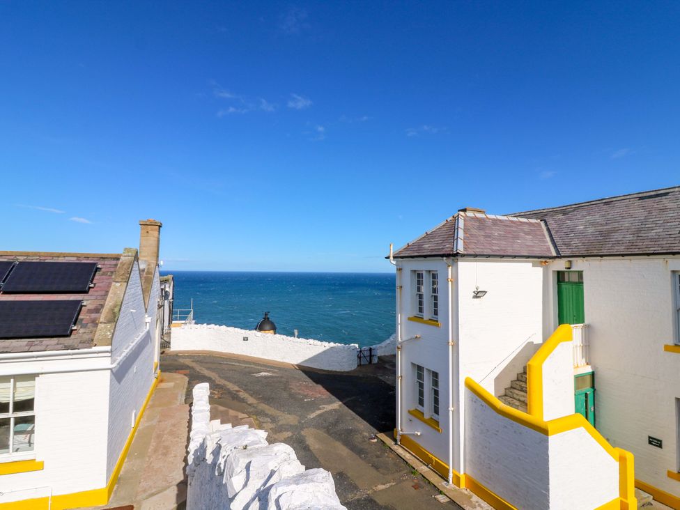 An outdoor view of buildings and the sea at The Flaghouse at The Lighthouse St Abbs