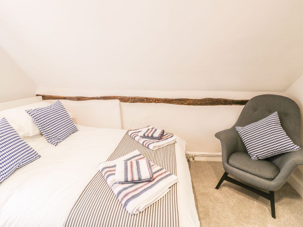 A bedroom with a bed and armchair at 4 Masons Court Stratford-upon-Avon