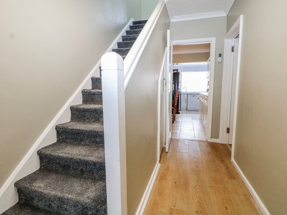 A hallway with staircase and kitchen access at The Retreat in Deal