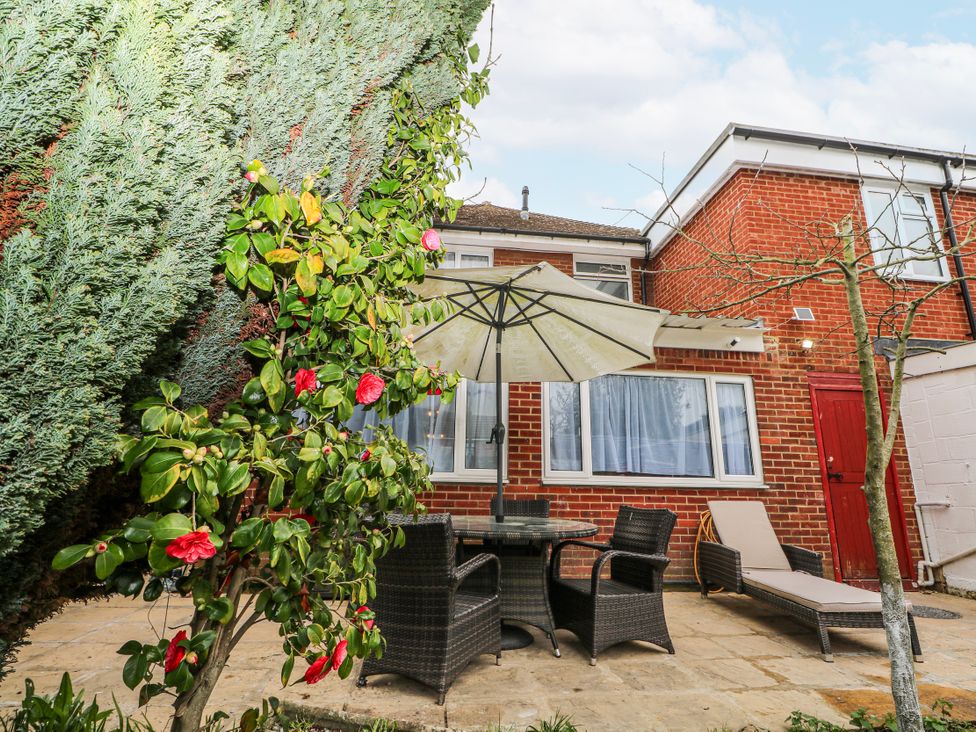 A garden with chairs and a table under an umbrella at The Retreat in Deal