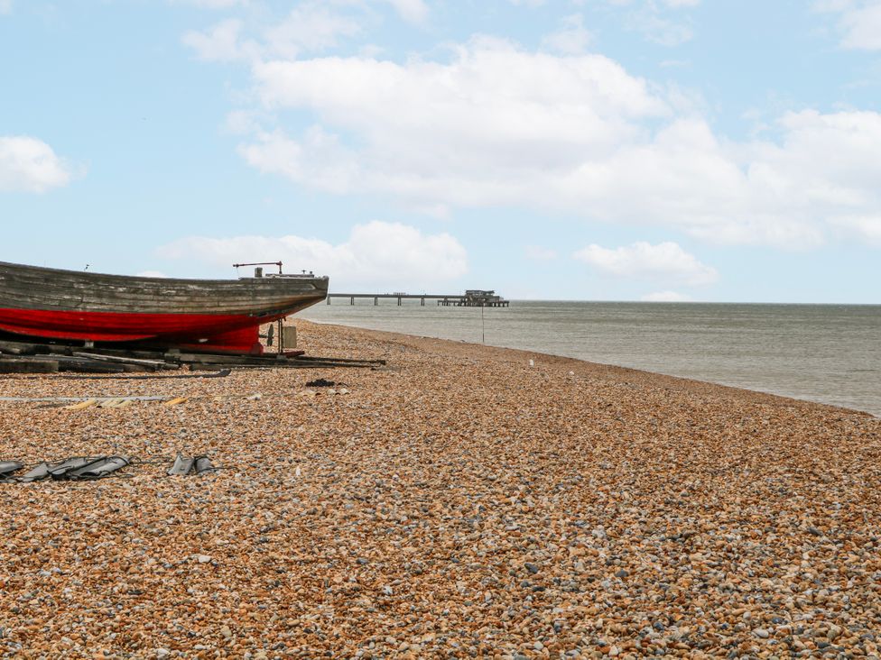 A beach with a boat and a pier at The Retreat in Deal