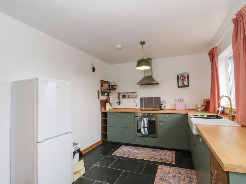 A kitchen with a refrigerator, sink, oven, and countertop at Doire An Daimh
