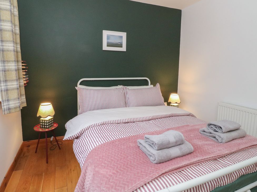A bedroom with a bed, lamp, towels and a photo at Doire An Daimh