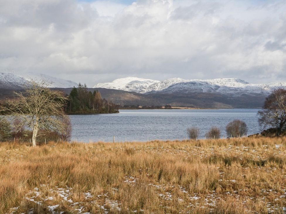 A landscape featuring mountains, a lake, and grass at Doire An Daimh