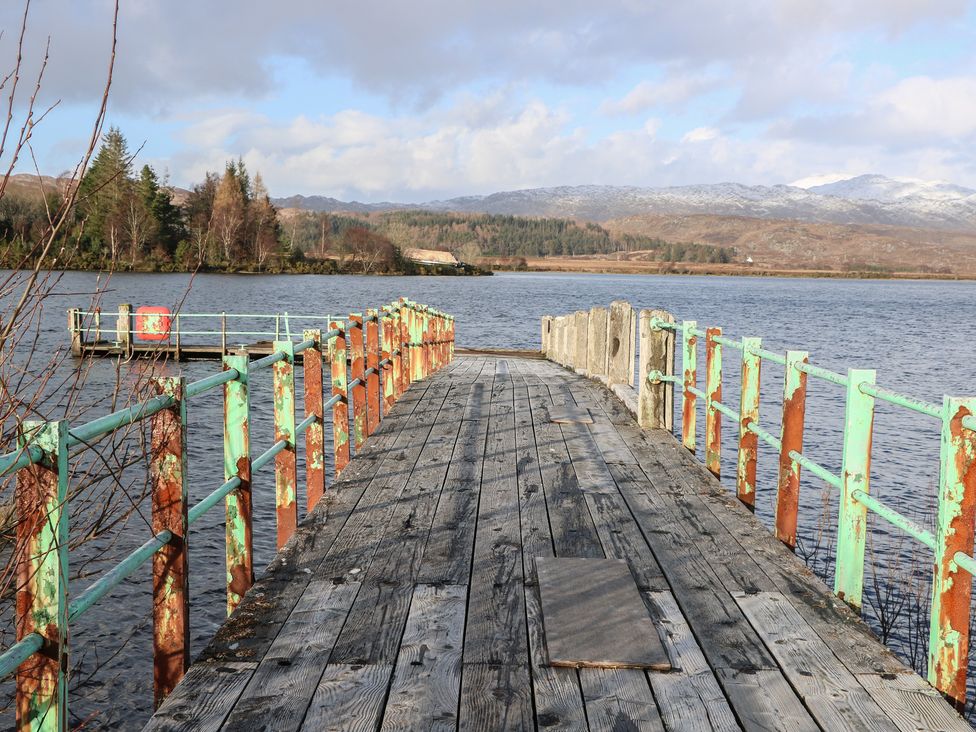 A pier extending over water surrounded by trees at Doire An Daimh 