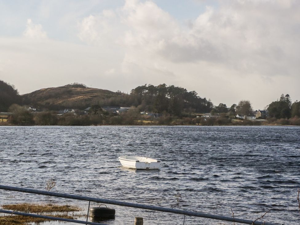 A boat on water with a hill and trees in the background at Doire An Daimh 