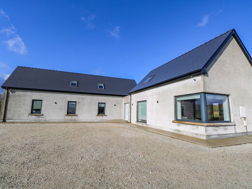 A house with windows and a door surrounded by gravel at An Tobar in Ballina